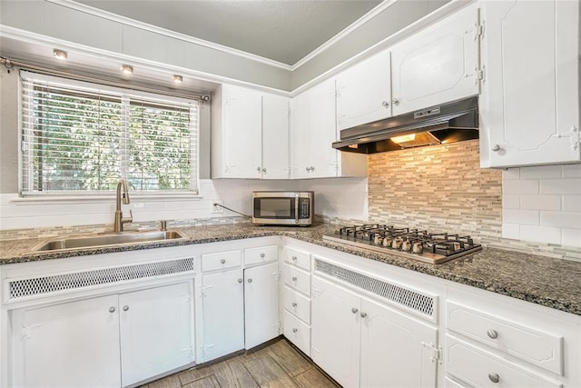 kitchen with white cabinetry, sink, stainless steel appliances, crown molding, and dark stone counters