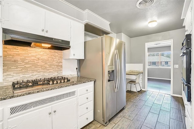 kitchen featuring tasteful backsplash, dark stone countertops, white cabinetry, and stainless steel appliances