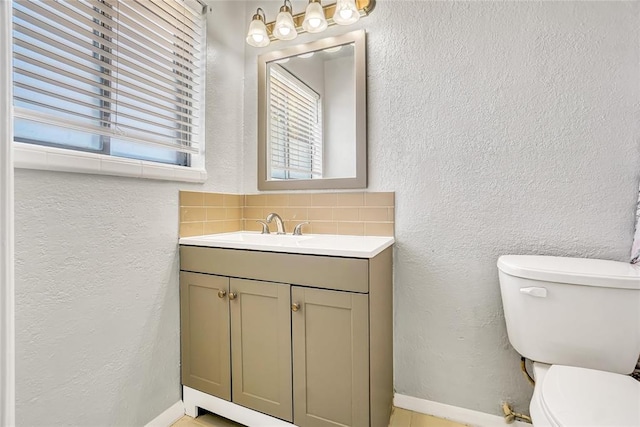 bathroom with decorative backsplash, toilet, and vanity