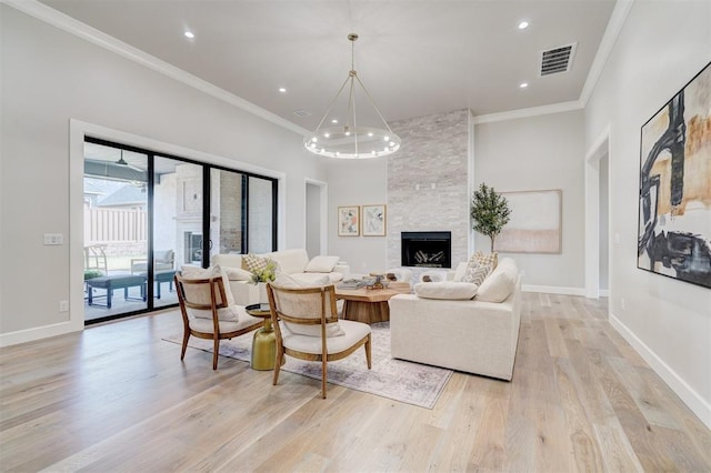 living room featuring crown molding, a fireplace, light hardwood / wood-style floors, and a notable chandelier