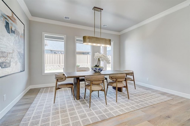 dining room featuring crown molding and light hardwood / wood-style floors