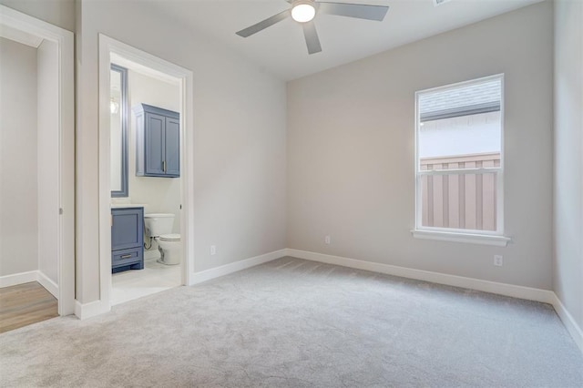 unfurnished bedroom with ensuite bath, ceiling fan, and light carpet