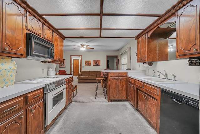 kitchen featuring kitchen peninsula, a kitchen bar, a textured ceiling, sink, and black appliances