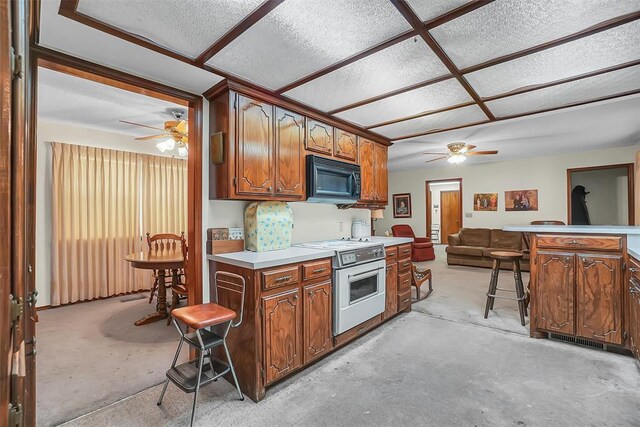 128 W Quail Dr, Cordell, OK 73632 - kitchen with electric range, a ceiling fan, black microwave, and a kitchen breakfast bar