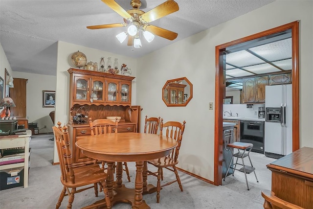 dining space with ceiling fan, sink, and a textured ceiling