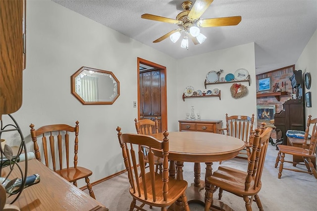 carpeted dining room featuring ceiling fan, a textured ceiling, and a brick fireplace