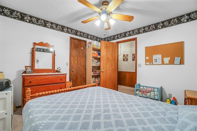 bedroom with ceiling fan, carpet floors, and a textured ceiling