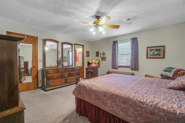 bedroom with ceiling fan, light colored carpet, and a textured ceiling