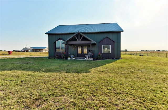 rear view of property with a lawn, french doors, and a rural view