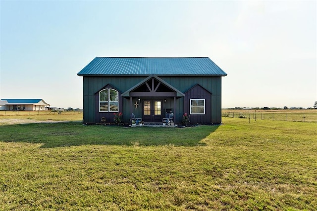 view of front of home with french doors, a front lawn, and a rural view