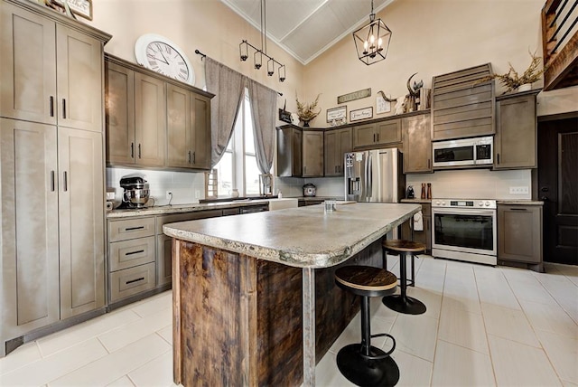 kitchen featuring appliances with stainless steel finishes, a breakfast bar, high vaulted ceiling, a center island, and hanging light fixtures