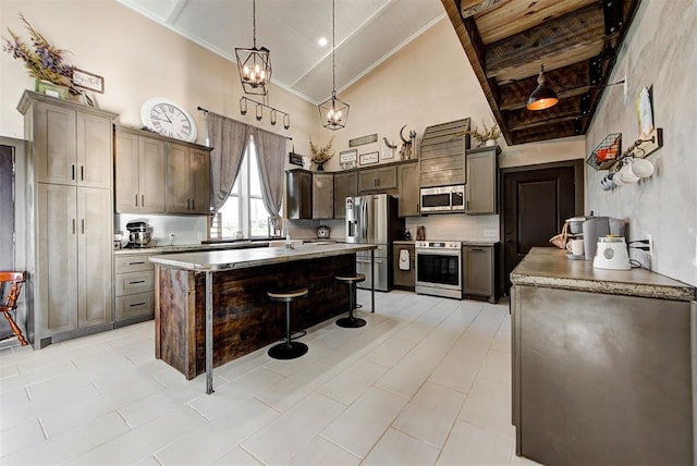 kitchen with high vaulted ceiling, decorative light fixtures, a breakfast bar area, a kitchen island, and appliances with stainless steel finishes