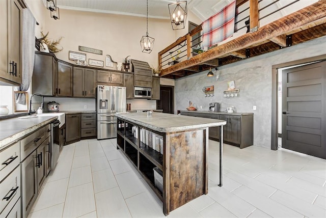 kitchen featuring appliances with stainless steel finishes, dark brown cabinets, light tile patterned floors, decorative light fixtures, and a kitchen island