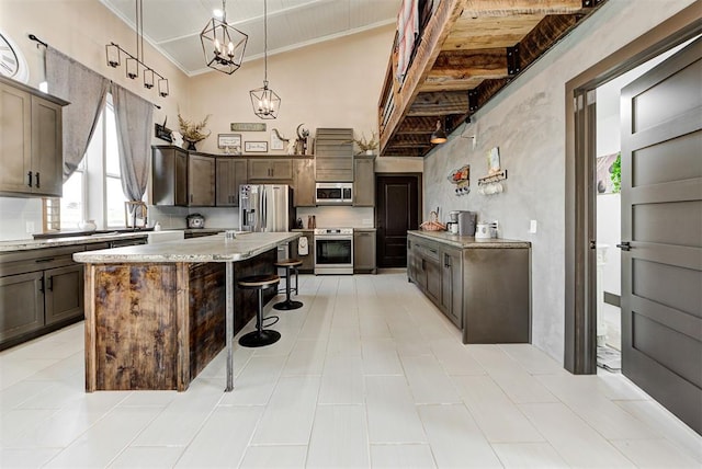 kitchen with a center island, high vaulted ceiling, an inviting chandelier, a kitchen breakfast bar, and appliances with stainless steel finishes