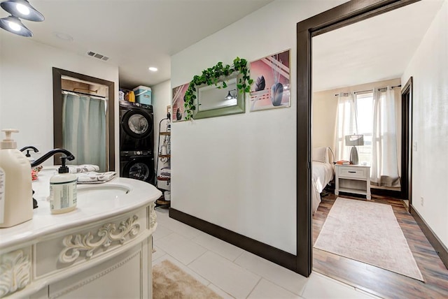 bathroom featuring hardwood / wood-style flooring, stacked washer / drying machine, and vanity