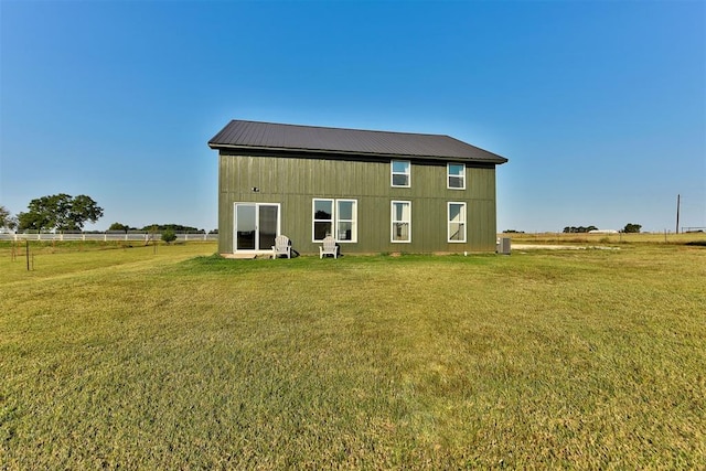 back of property featuring a rural view, a yard, and an outbuilding