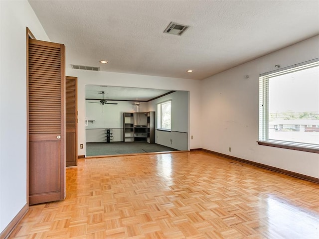 unfurnished living room with ceiling fan, light parquet flooring, and a textured ceiling