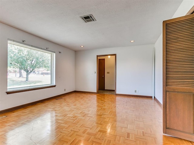 spare room with a textured ceiling and light parquet flooring