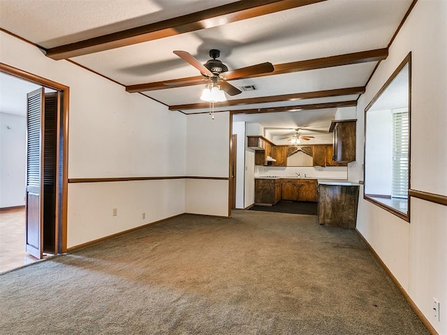 unfurnished living room featuring carpet flooring, ceiling fan, and beam ceiling