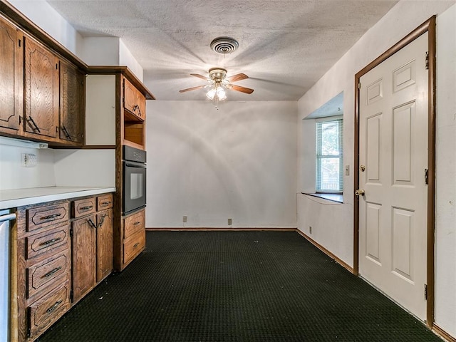 kitchen with dark colored carpet, a textured ceiling, oven, and ceiling fan