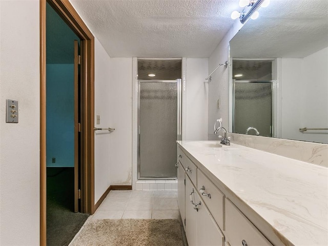 bathroom with tile patterned floors, vanity, an enclosed shower, and a textured ceiling