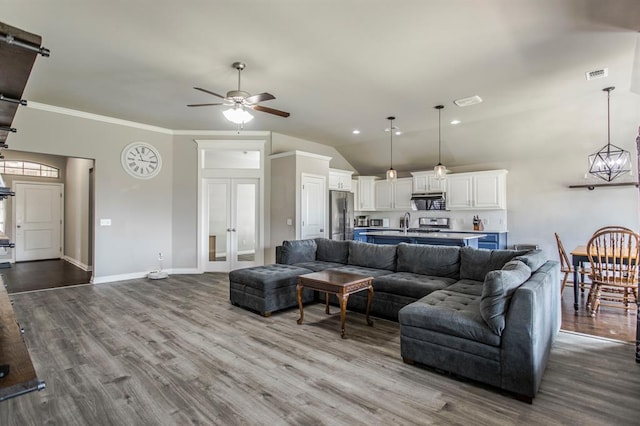 living room featuring light wood-type flooring, vaulted ceiling, ceiling fan, and crown molding