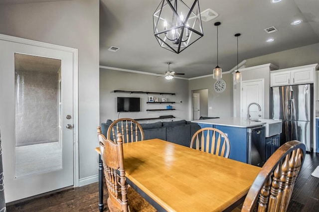 dining space with crown molding, sink, dark wood-type flooring, and ceiling fan with notable chandelier