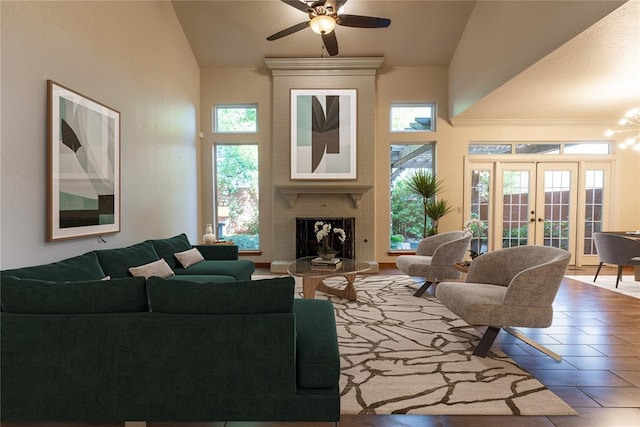 tiled living room featuring a large fireplace, ceiling fan, french doors, and high vaulted ceiling