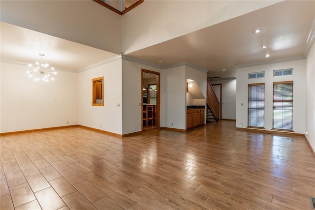 unfurnished living room featuring a chandelier, light hardwood / wood-style floors, and ornamental molding