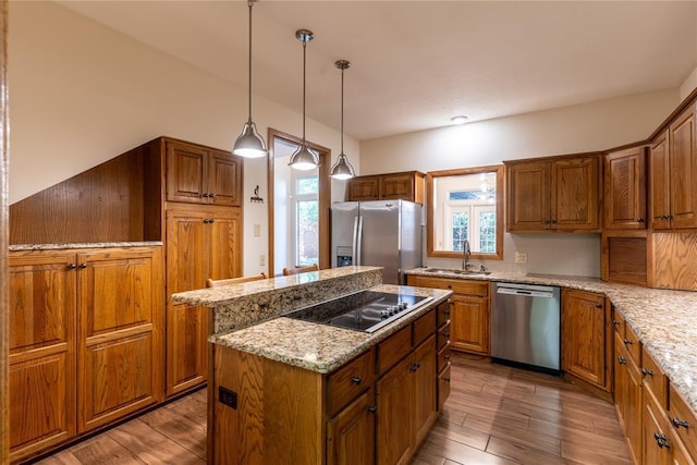 kitchen with a center island, sink, hardwood / wood-style flooring, light stone countertops, and stainless steel appliances