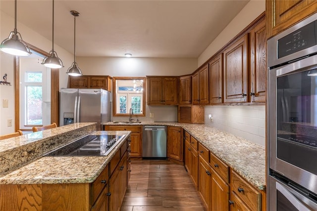 kitchen featuring light stone countertops, sink, dark wood-type flooring, stainless steel appliances, and decorative light fixtures