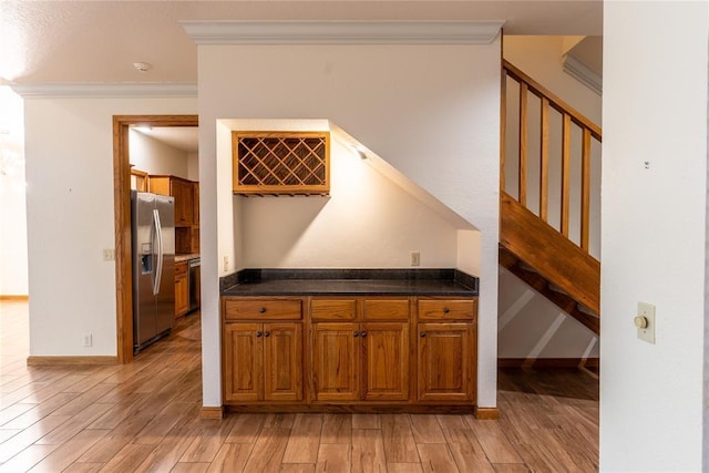 bar featuring stainless steel fridge with ice dispenser, ornamental molding, and light hardwood / wood-style flooring