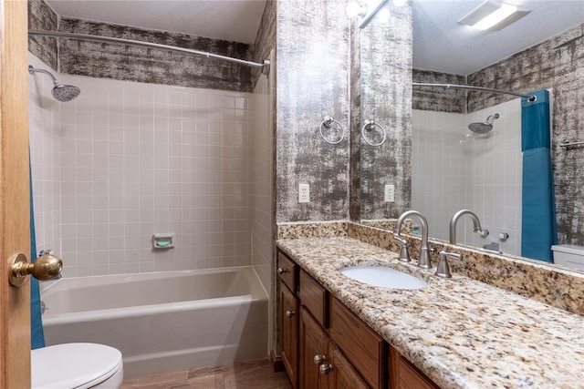 full bathroom with vanity, tiled shower / bath combo, a textured ceiling, and toilet