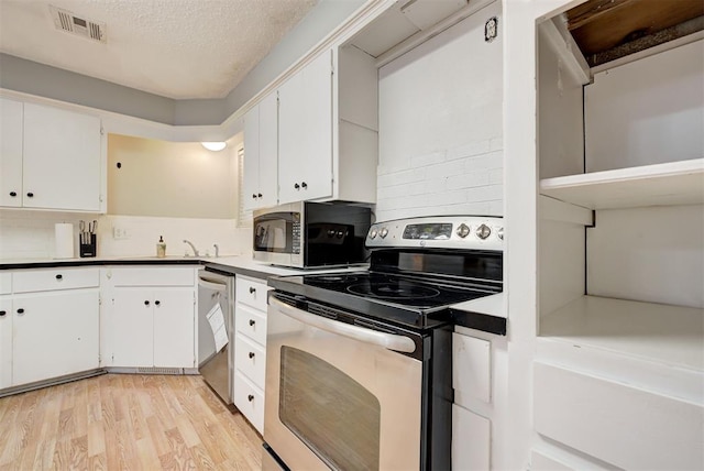 kitchen with light hardwood / wood-style flooring, white cabinets, stainless steel appliances, and a textured ceiling