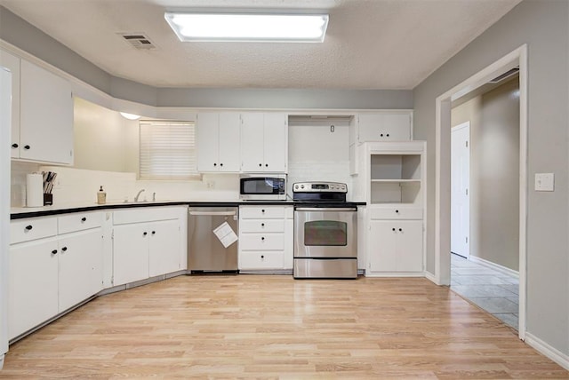 kitchen with white cabinetry, light wood-type flooring, and appliances with stainless steel finishes