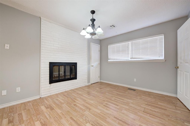 unfurnished living room featuring a fireplace, light hardwood / wood-style floors, and a notable chandelier