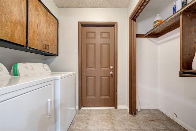 laundry area with cabinets, a textured ceiling, and washing machine and clothes dryer