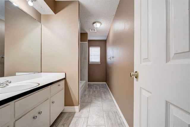 bathroom featuring a shower, vanity, and a textured ceiling