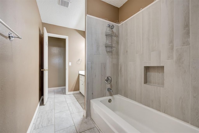 bathroom featuring vanity, a textured ceiling, and tiled shower / bath combo