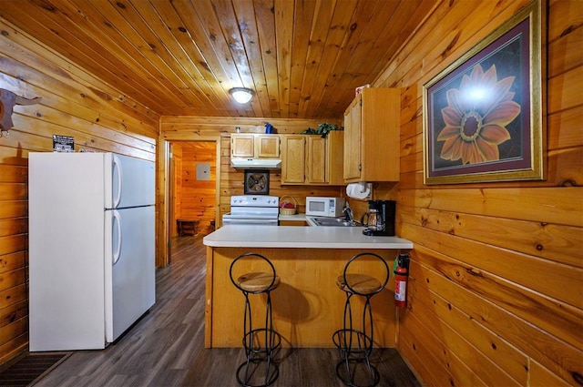 kitchen with kitchen peninsula, wood walls, dark wood-type flooring, and white appliances