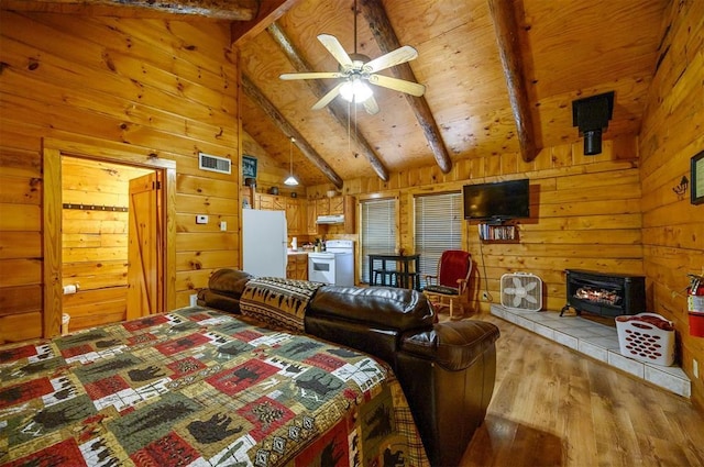 130 Wildwood Trl, Broken Bow, OK 74728 - bedroom featuring freestanding refrigerator, a wood stove, wood finished floors, and wood walls