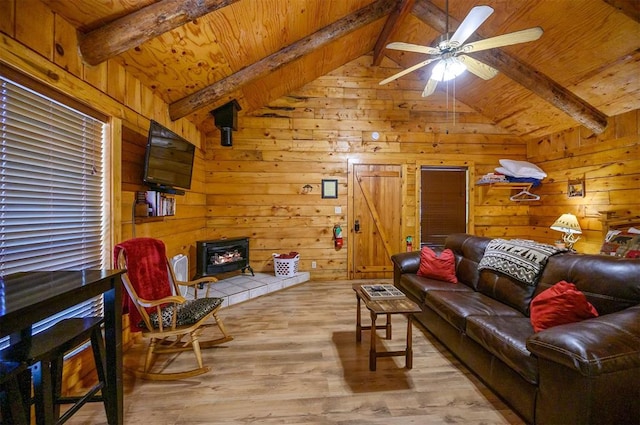 living room with vaulted ceiling with beams, wood walls, light wood-type flooring, and ceiling fan