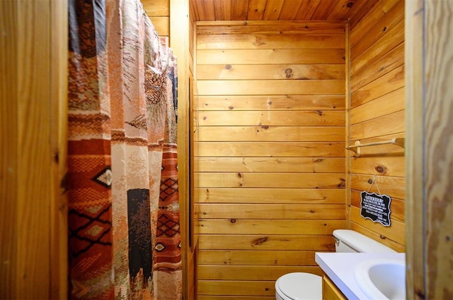 bathroom featuring vanity, toilet, wood ceiling, and wooden walls