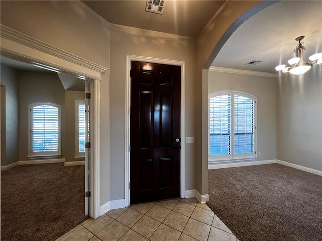 foyer entrance with ornamental molding, light colored carpet, an inviting chandelier, and a healthy amount of sunlight