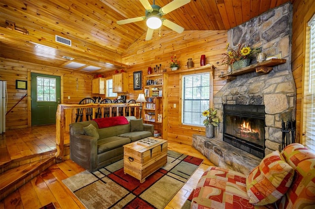 living room featuring wood ceiling, light wood-type flooring, wooden walls, and vaulted ceiling