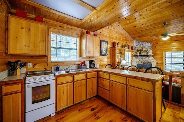 183 Pine Meadow Ln, Broken Bow, OK 74728 - kitchen featuring white range with electric cooktop, a peninsula, wooden walls, light wood-style floors, and lofted ceiling