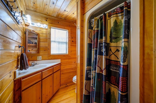 bathroom featuring wooden ceiling, hardwood / wood-style floors, toilet, wooden walls, and vanity