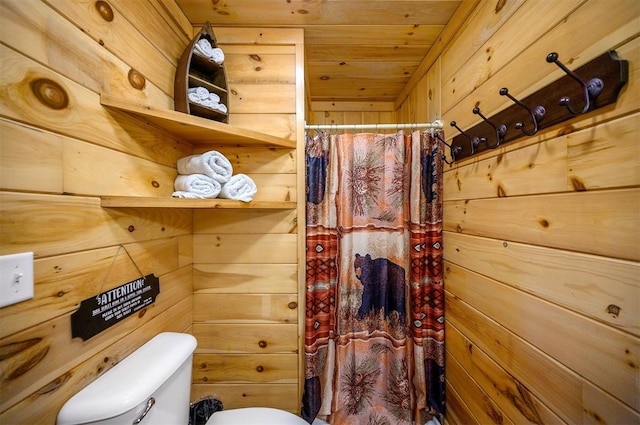 bathroom with toilet, wooden ceiling, and wood walls