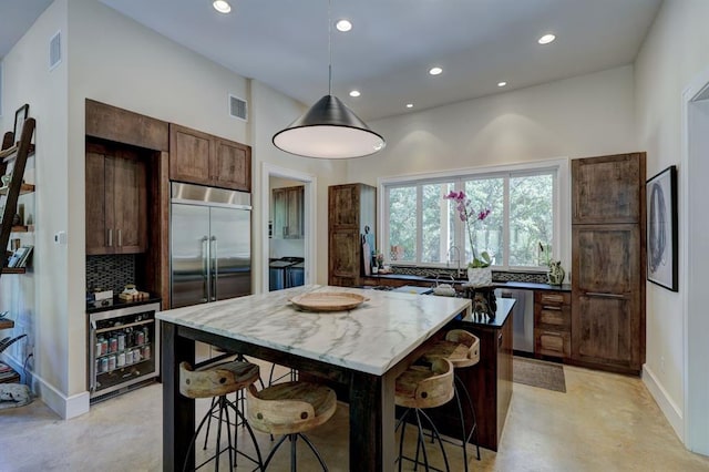 kitchen featuring hanging light fixtures, stainless steel appliances, a kitchen breakfast bar, backsplash, and a kitchen island