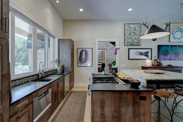 kitchen with sink, hanging light fixtures, light hardwood / wood-style floors, a kitchen bar, and a kitchen island